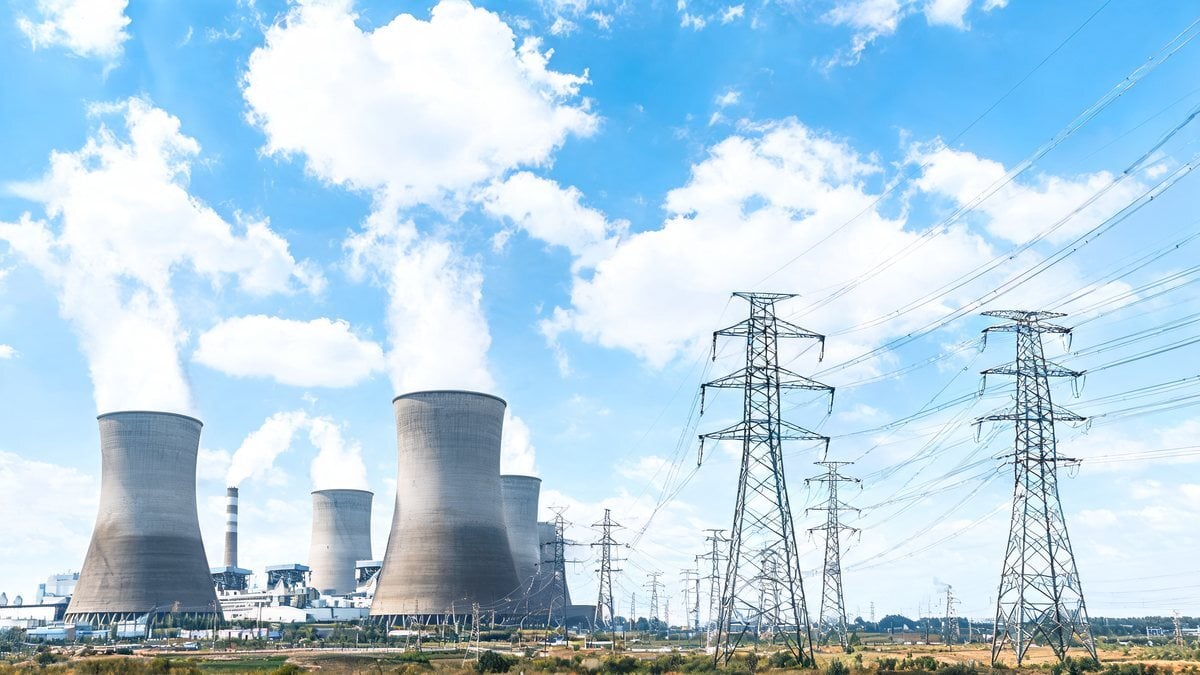 Power plant stacks and high voltage pylons under a blue sky