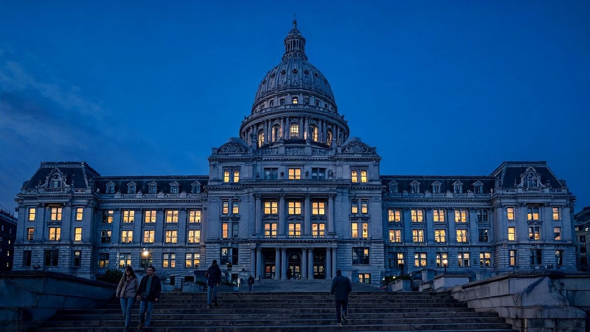 A domed city hall building at dusk with lit windows